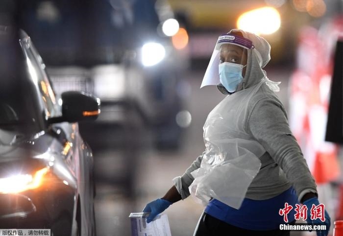 當(dāng)?shù)貢r間12月18日，英國政府公布的數(shù)據(jù)顯示，當(dāng)天英國新增奧密克戎毒株感染病例10059例。鑒于奧密克戎毒株感染病例激增，住院人數(shù)不斷上升，倫敦市長宣布倫敦進入“重大事故”狀態(tài)。圖為倫敦的一個免下車檢測中心，一名醫(yī)務(wù)工作者正準(zhǔn)備對司機進行核酸檢測。