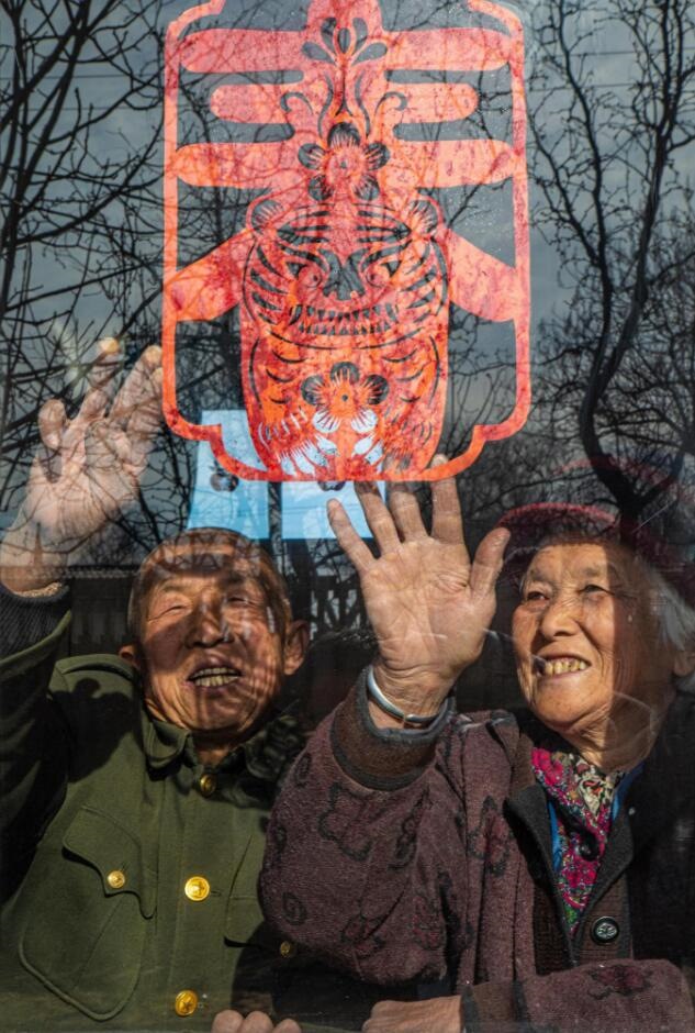 臘月里，霍州市師莊鄉(xiāng)馮南垣村村民師榮光(左)在災(zāi)后重建的新家里貼窗花。(霍州市委宣傳部供圖)