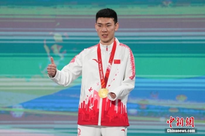 3月6日，梁景怡在延慶頒獎(jiǎng)廣場(chǎng)領(lǐng)獎(jiǎng)臺(tái)上豎起大拇指。當(dāng)日，在國(guó)家高山滑雪中心舉行的北京2022年冬殘奧會(huì)殘奧高山滑雪男子超級(jí)大回轉(zhuǎn)—站姿決賽中，中國(guó)選手梁景怡奪得冠軍。 <a target='_blank' href='/'>中新社</a>記者 楊華峰 攝