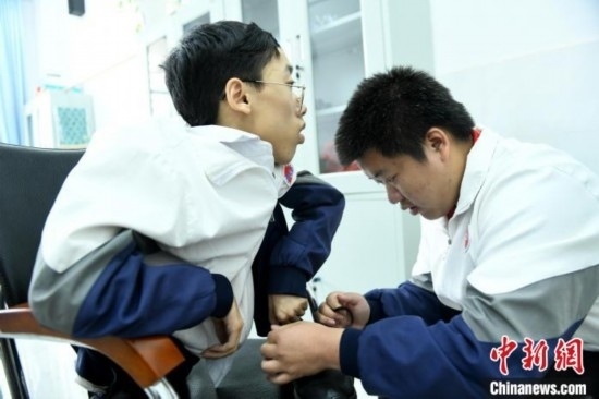 江西省南康中學(xué)北校區(qū)的高三學(xué)生朱金祥(右)正在給鐘華強(qiáng)(左)系好鞋帶。 卓忠偉 攝