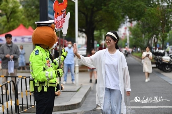 6月7日上午9時(shí)，隨著鈴聲的響起，2023年江西高考正式開(kāi)考，江西省的53.57萬(wàn)考生以縣（區(qū)）為單位隨機(jī)安排在全省256個(gè)考點(diǎn)、18968個(gè)考場(chǎng)參加高考。圖為“小熊交警”和考生擊掌鼓勵(lì)。 人民網(wǎng)記者 時(shí)雨攝