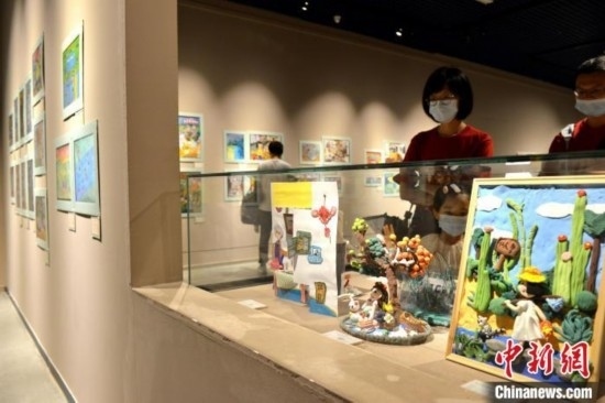 圖為家長(zhǎng)帶著孩子參觀展覽。呂明 攝