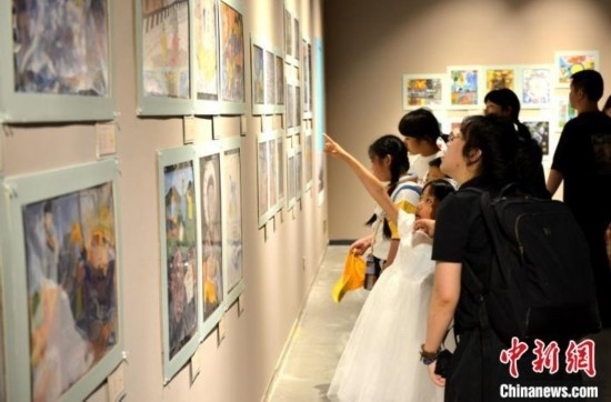 圖為家長(zhǎng)帶著孩子參觀展覽。呂明 攝