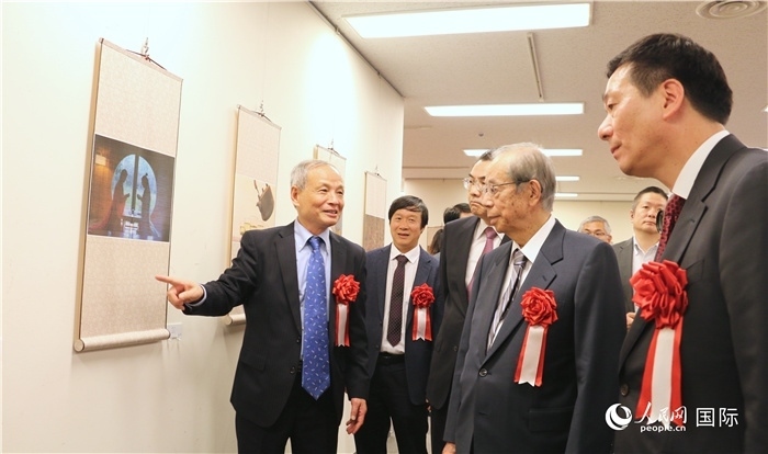 “湖州印象”攝影展主創(chuàng)、世界華人攝影協(xié)會(huì)副會(huì)長(zhǎng)馮學(xué)敏向吳江浩大使、福田康夫前首相等嘉賓介紹展出作品。（人民網(wǎng) 許可攝）