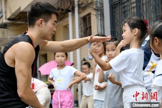 圖為大學(xué)生志愿者在組織孩子們參加體育健身活動(dòng)。廖光福 攝