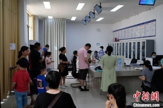 圖為在戶籍辦證廳內(nèi)排隊(duì)等待的家長(zhǎng)和孩子。劉俊聰 攝