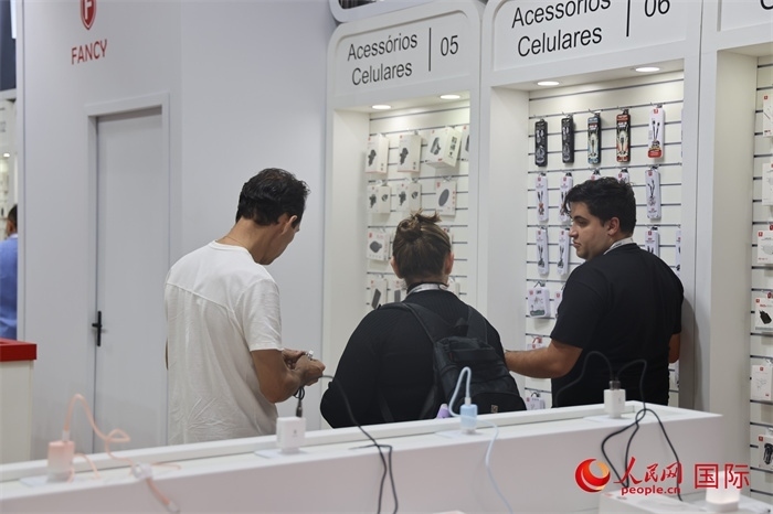 幾名參觀者在一個展臺前了解手機配件。（人民網(wǎng)記者 時元皓攝）