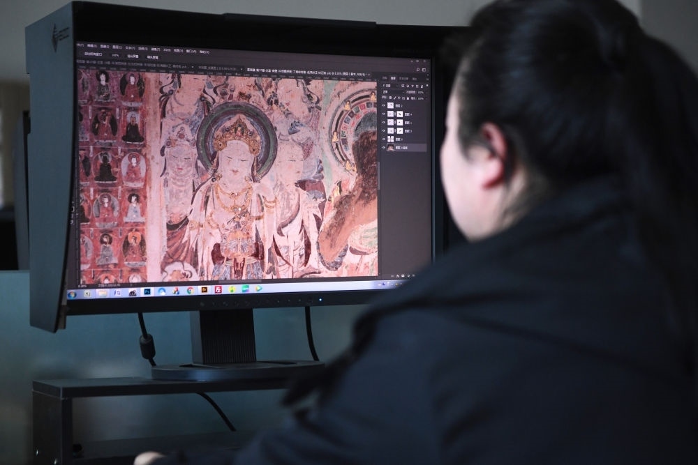 敦煌研究院文物數(shù)字化保護(hù)團(tuán)隊(duì)圖像處理人員年海麗在拼接壁畫圖像（2023年4月25日攝）。數(shù)字化探索為莫高窟的保護(hù)與傳承開辟了全新路徑，數(shù)字技術(shù)讓敦煌文物走出洞窟，跨出國(guó)門，走向“永久保存、永續(xù)利用”。新華社記者 陳斌 攝