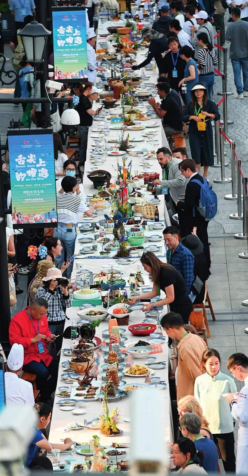 市民和游客在寧波舉辦的第三屆中國(guó)—中東歐國(guó)家博覽會(huì)暨國(guó)際消費(fèi)品博覽會(huì)上品嘗融合中國(guó)和中東歐美食的長(zhǎng)桌宴（2023年5月15日攝）。黃宗治攝/本刊