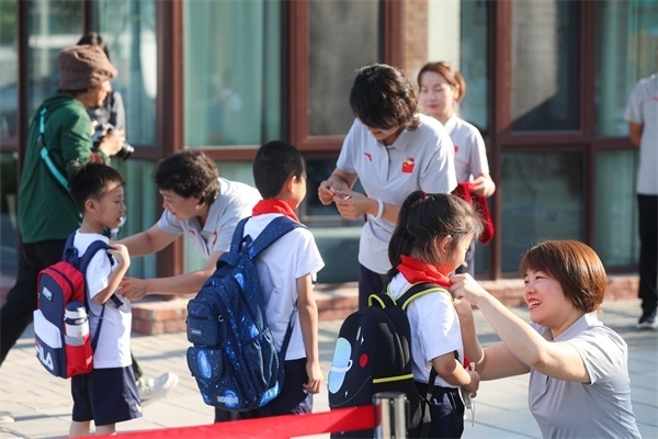 8月30日，雄安史家胡同小學(xué)學(xué)生體驗(yàn)學(xué)校生活。老師為學(xué)生佩戴?；?。