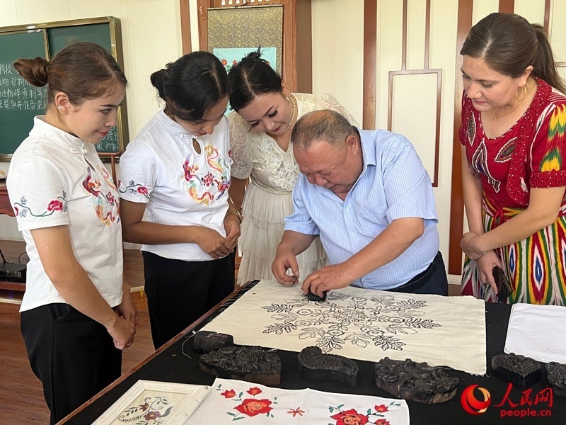 國(guó)家級(jí)非物質(zhì)文化遺產(chǎn)模戳印花布技藝傳承人吾吉阿西木?吾舒爾展示模戳印花布的制作過程。人民網(wǎng)記者 常雪梅攝