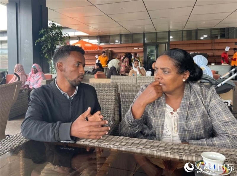 約漢斯（圖左）與德貝拉在友誼廣場咖啡廳交談。人民網(wǎng)記者 趙艷紅攝