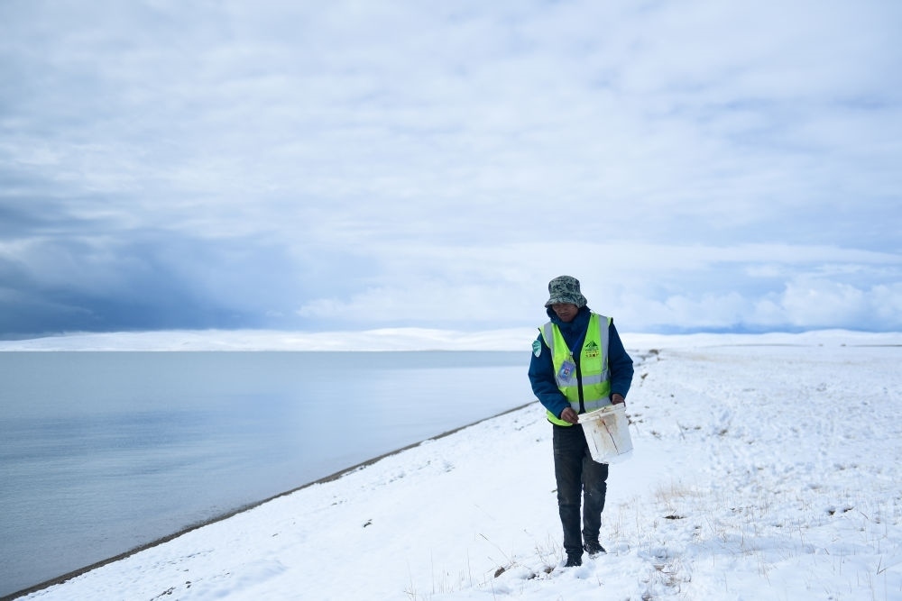 2021年10月20日，在青海省果洛藏族自治州瑪多縣扎陵湖鄉(xiāng)勒那村，三江源國(guó)家公園黃河源園區(qū)生態(tài)管護(hù)員在扎陵湖邊撿拾垃圾。新華社記者 張龍 攝