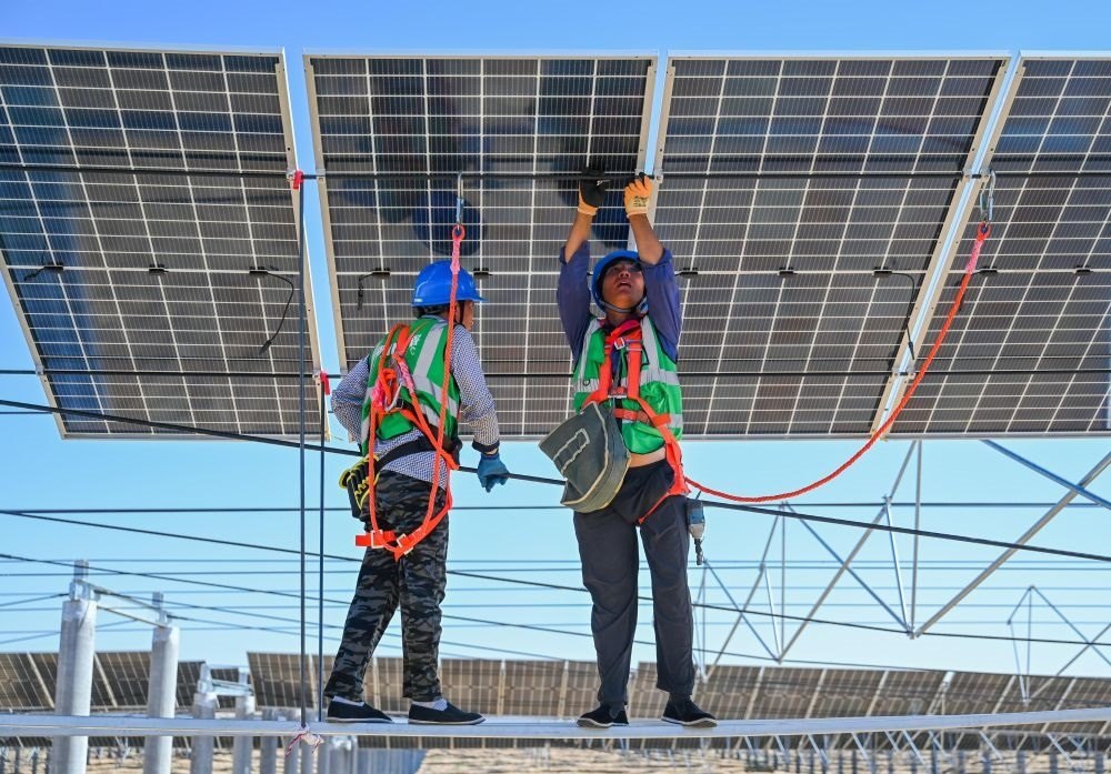 2023年7月22日，工人在位于內(nèi)蒙古杭錦旗庫(kù)布其沙漠億利生態(tài)示范區(qū)的蒙西基地庫(kù)布其200萬(wàn)千瓦光伏治沙項(xiàng)目工地安裝光伏板。新華社記者 劉磊 攝