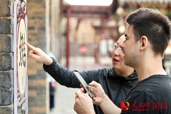 選手安德烈（俄羅斯）在老師指導(dǎo)下學(xué)習(xí)墻壁上張貼的生僻字。人民網(wǎng) 盧鵬宇攝