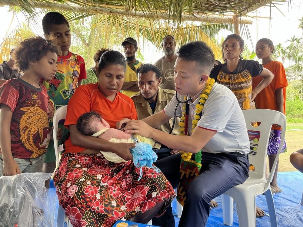 2023年8月5日，在巴布亞新幾內(nèi)亞中央省的一個(gè)村莊里，第12批援巴新中國(guó)醫(yī)療隊(duì)副隊(duì)長(zhǎng)、新生兒科副主任醫(yī)師劉振球?yàn)楫?dāng)?shù)貗雰郝犜\檢查。新華社發(fā)（第12批援巴新中國(guó)醫(yī)療隊(duì)供圖）
