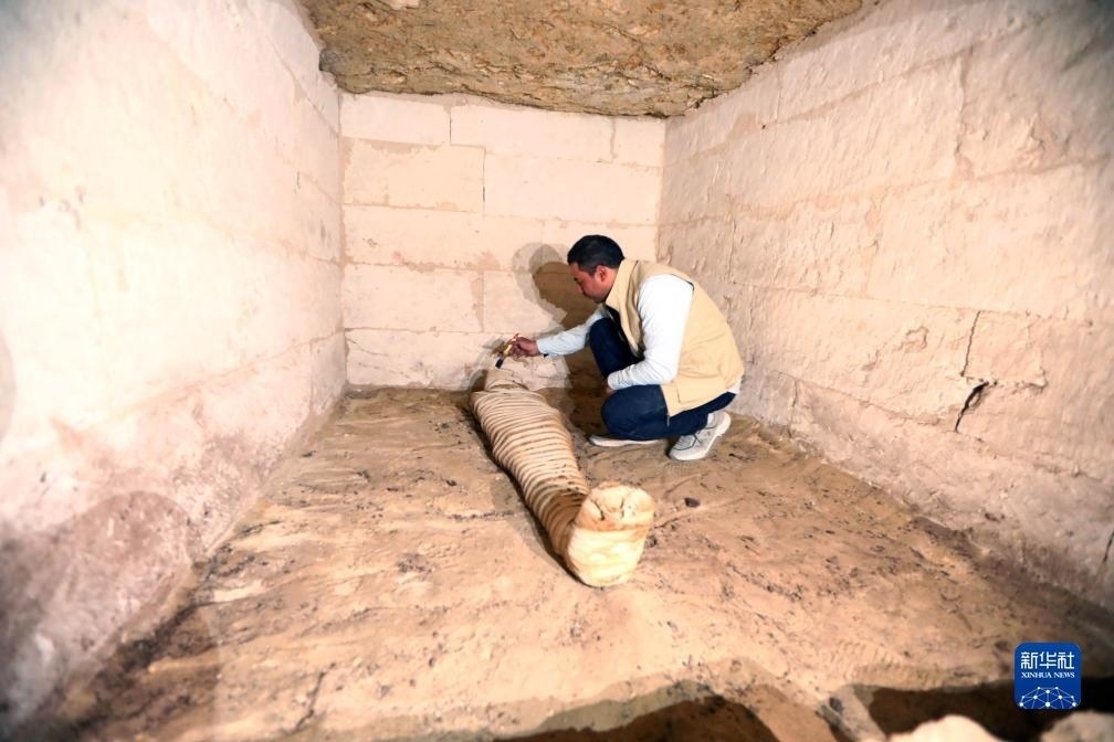 10月15日，在埃及明亞省考古現(xiàn)場(chǎng)，考古人員清理一座石鑿墓中的木乃伊。新華社發(fā)（艾哈邁德·戈馬攝）