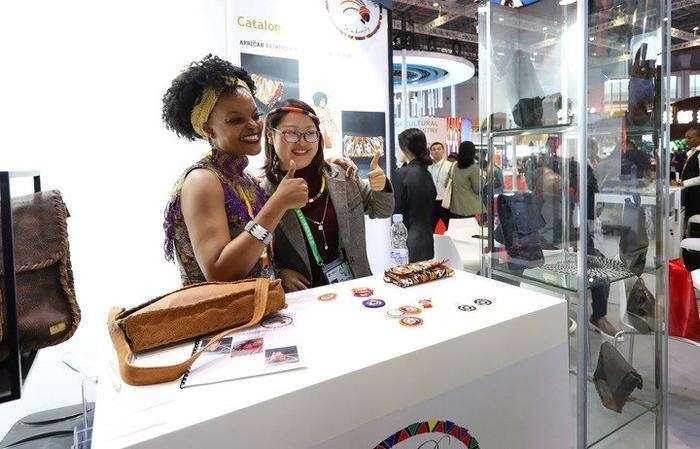 11月6日，一位參觀者（右）在第六屆進(jìn)博會(huì)國家展南非展臺(tái)試戴傳統(tǒng)首飾。