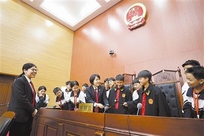 圖③：同學們穿法袍、敲法槌，爭做“小法官”。