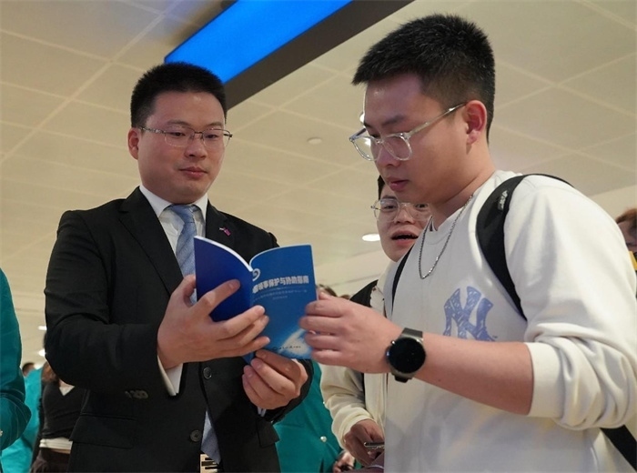 工作人員（左一）在發(fā)放《中國領(lǐng)事保護與協(xié)助指南》。 中國駐迪拜總領(lǐng)事館供圖