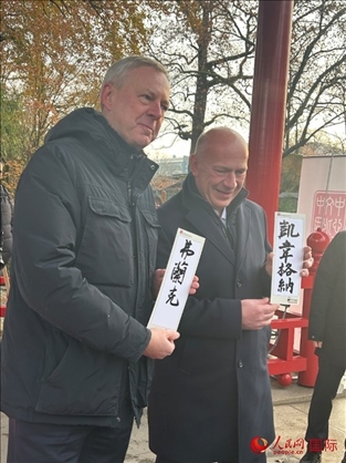 柏林市長韋格納（右）、動物園監(jiān)事會主席布魯克曼（左）手持中國文化中心工作人員現(xiàn)場手書的中文名字。人民網(wǎng)記者 徐馨攝