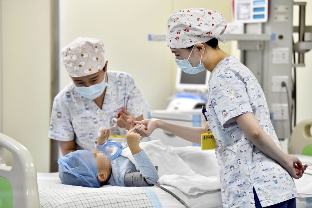 在山東省棗莊市婦幼保健院兒童ICU病房，醫(yī)護(hù)人員為完成靶向治療藥物諾西那生鈉的4歲脊髓性肌萎縮癥患兒加油鼓勁（2022年1月1日攝）。諾西那生鈉注射液是我國首個獲批治療脊髓性肌萎縮癥的進(jìn)口藥物，2019年進(jìn)入中國市場時，每針價格近70萬元。在2021年國家醫(yī)保目錄藥品談判中，以3.3萬元每針的價格進(jìn)入新版醫(yī)保藥品目錄。新華社記者 郭緒雷 攝