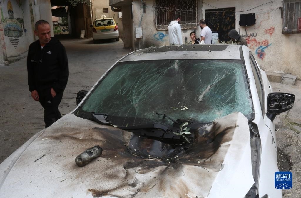 12月17日，在約旦河西岸城市圖勒凱爾姆附近的一處難民營，人們查看在沖突中損毀的車輛。新華社發(fā)（尼達爾·艾仕塔耶攝）