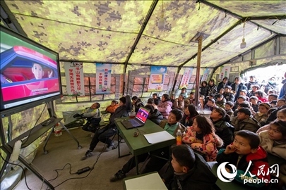 12月22日，在積石山縣大河家鎮(zhèn)大河村安置點，陸軍76集團軍某旅搭建的“臨時學(xué)校”內(nèi)，小朋友正在看動畫片。人民網(wǎng)記者 翁奇羽攝