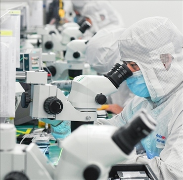 在位于武漢中國光谷的光電器件研發(fā)制造商——武漢光迅科技股份有限公司生產(chǎn)車間內(nèi)，技術(shù)人員在光模塊生產(chǎn)線作業(yè)（2023年4月11日攝）。程敏攝/本刊