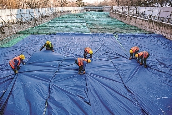 1月3日，房山區(qū)東風(fēng)街道，工人正在修復(fù)的河道內(nèi)給混凝土鋪設(shè)保溫布。