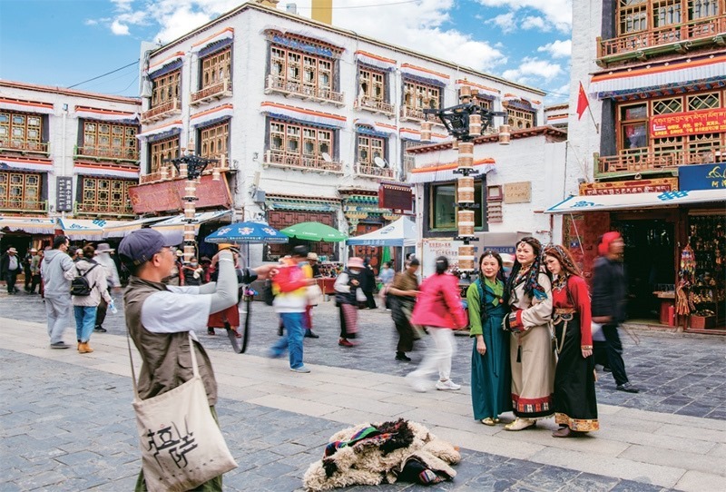 千年八廓街，見證民族團(tuán)結(jié)。2021年7月，習(xí)近平總書記來(lái)到位于西藏拉薩老城區(qū)的八廓街，感慨地說(shuō)：“千年八廓街，是我們各民族建起來(lái)的八廓街。各民族文化在這里交流交往交融，我們中華民族的大家庭在這里其樂(lè)融融?！眻D為2023年6月13日，游客身著藏裝在八廓街拍照留念。 新華社記者 姜帆/攝