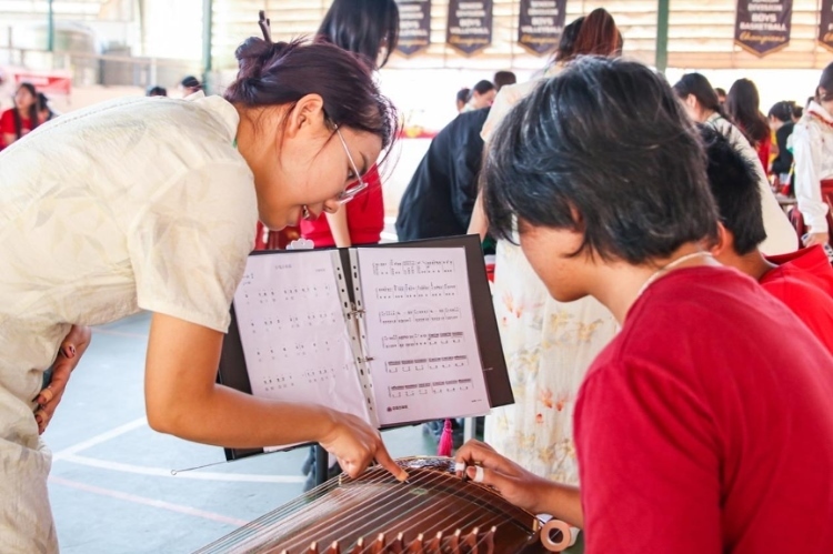 志愿者教師指導(dǎo)學(xué)生彈奏古箏?；顒又鬓k方供圖