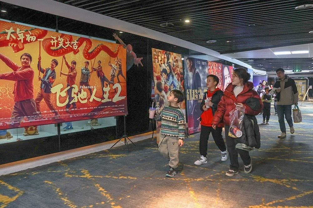△ 2024年2月16日，在江西贛州一家電影院，觀眾從春節(jié)檔電影的宣傳展板前走過。