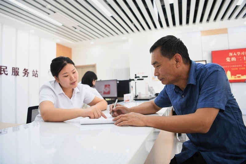 2023年5月23日，河北雄安新區(qū)容東片區(qū)南文營(yíng)社區(qū)居民（右）在社區(qū)便民服務(wù)站辦理業(yè)務(wù)。