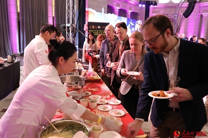 當?shù)貢r間3月7日晚，華盛頓聯(lián)合車站廣場舉行駐美使團“使館主廚挑戰(zhàn)賽”。圖為當?shù)孛癖娫谥袊古_前體驗中國美食。人民網(wǎng)記者 李志偉攝