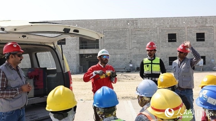 穆薩瓦爾(圖中紅衣人）現(xiàn)場演示工具操作規(guī)范。人民網(wǎng)記者 管克江攝