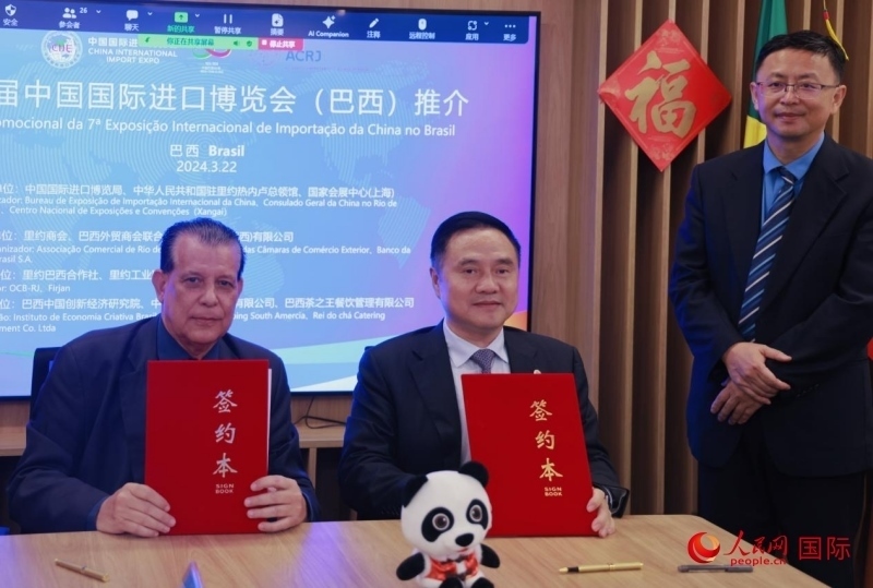 巴西外貿(mào)商會聯(lián)合會會長阿代爾·羅伯托（左）與中國國際進口博覽局副局長吳政平（中）現(xiàn)場簽訂協(xié)議。人民網(wǎng)記者 宋亦然攝