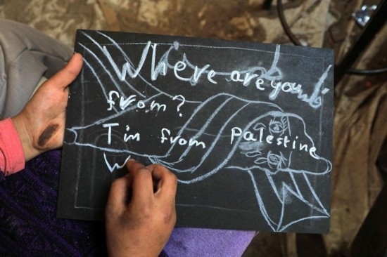 2023年12月28日，一名學(xué)生在加沙地帶南部城市拉法一所學(xué)校的臨時(shí)教室中寫下“我來自巴勒斯坦”的字樣。新華社發(fā)（里澤克·阿卜杜勒賈瓦德攝）