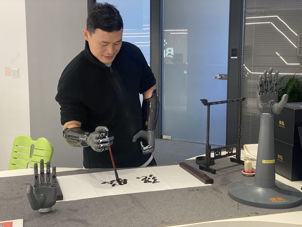 2024年3月29日，在浙江強腦科技有限公司展廳內(nèi)，失去雙手的產(chǎn)品體驗官倪敏成依靠智能仿生手寫毛筆字。新華社記者 魏一駿 攝