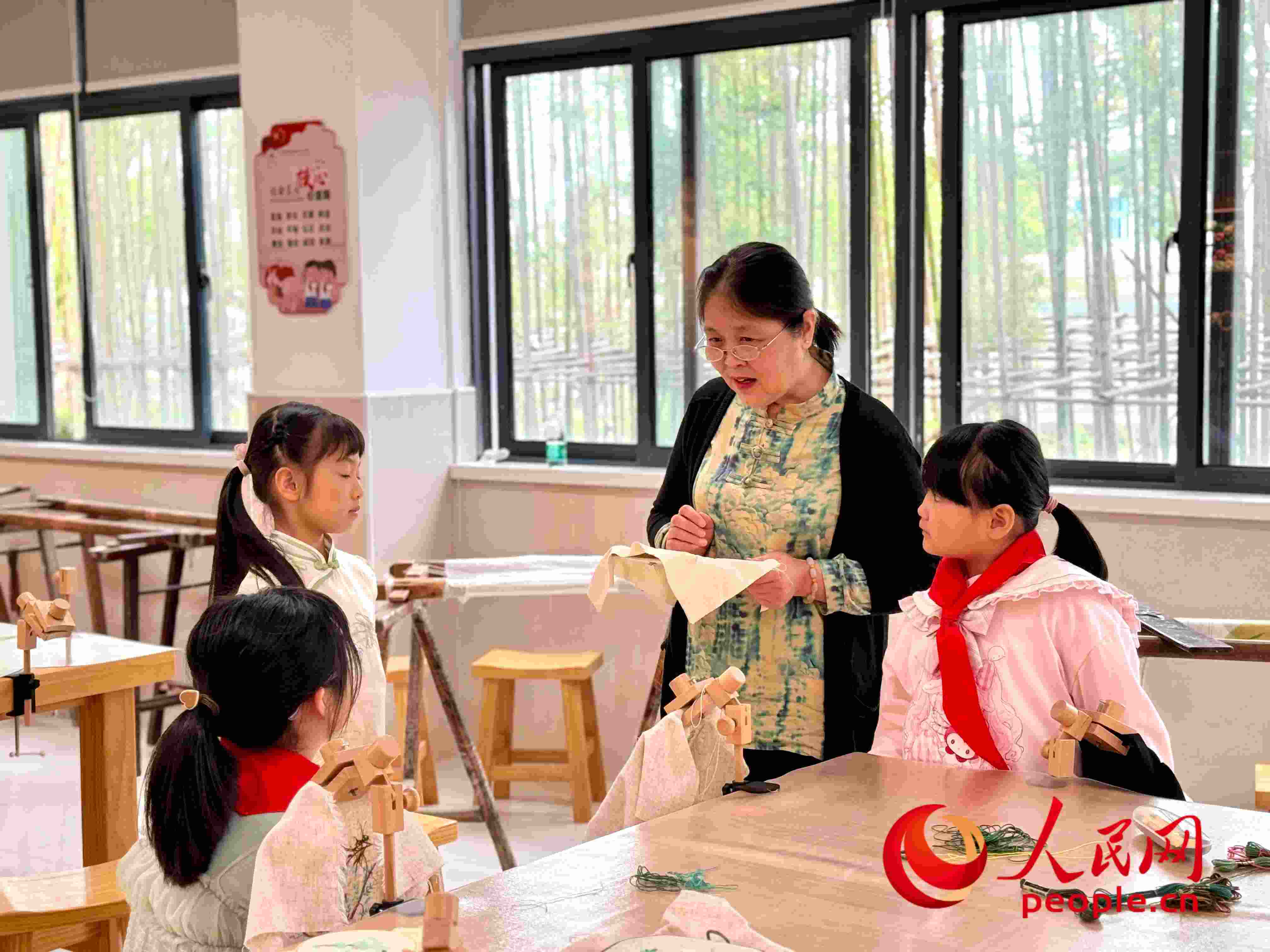 顧建珍（左三）在教孩子們刺繡知識(shí)。人民網(wǎng) 周靜圓攝