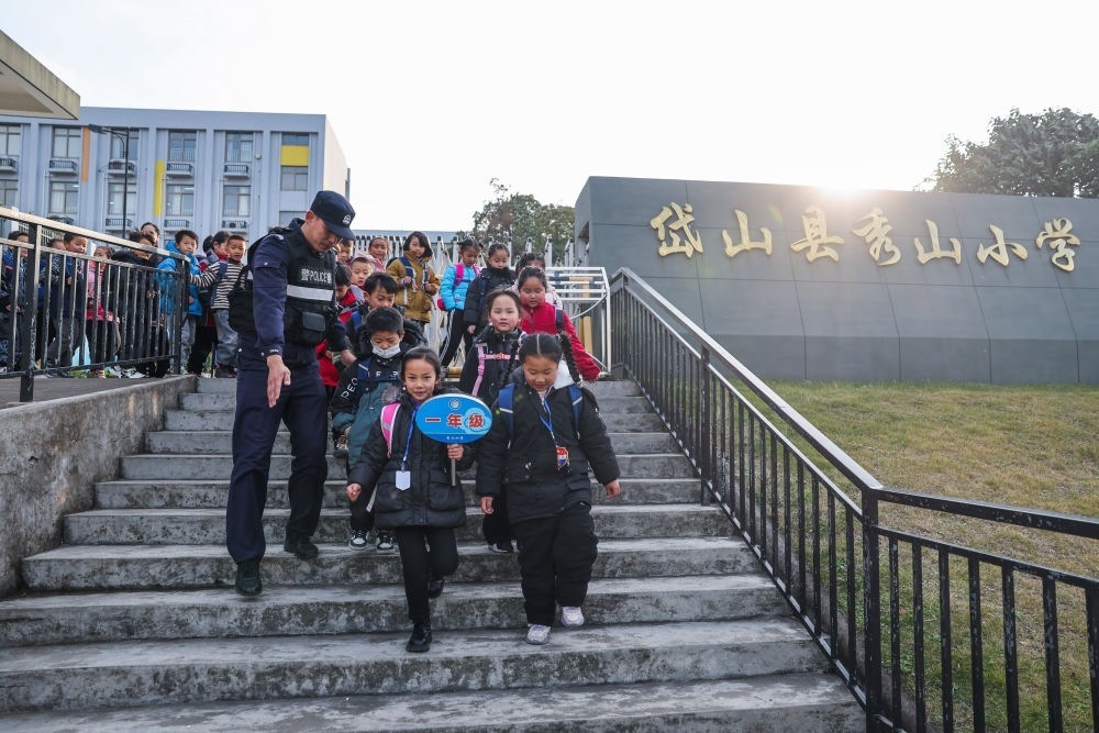 2023年12月20日，秀山派出所民警在秀山小學放學時間參與“護學崗”維持秩序，同時接獨自放學的學生去“民生小鋪”。浙江省舟山市岱山縣公安局秀山派出所聯(lián)合鄉(xiāng)鎮(zhèn)、社區(qū)成立“民生小鋪”，為當?shù)鼐用?、外來務工人員及其子女等服務，協(xié)助解決外來務工人員在工作、生活等方面的矛盾和問題，助力鄉(xiāng)鎮(zhèn)基層治理。新華社記者 徐昱 攝