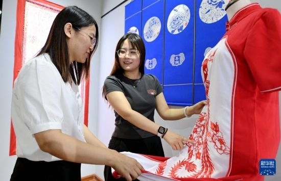5月31日，在衡水市阜城縣一家剪紙工作室，游客在觀賞帶有剪紙元素的旗袍。