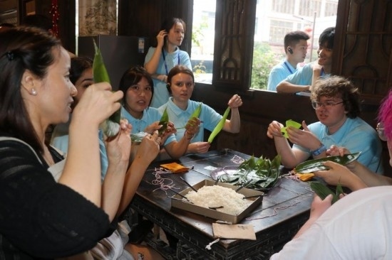 6月9日，美國青年代表在重慶永川松溉古鎮(zhèn)體驗包粽子。新華社記者 周思宇 攝