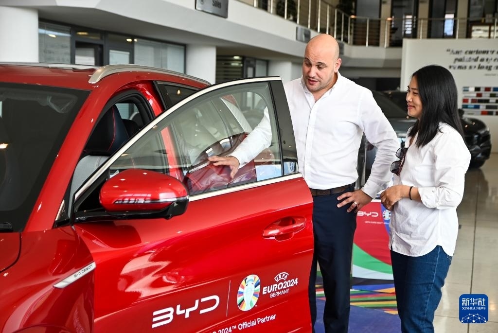2024年5月29日，在馬耳他比爾基卡拉，馬耳他哈桑-扎米特汽車公司首席執(zhí)行官德古阿拉（左）介紹一輛比亞迪純電動汽車。新華社發(fā)（喬納森·博格 攝）