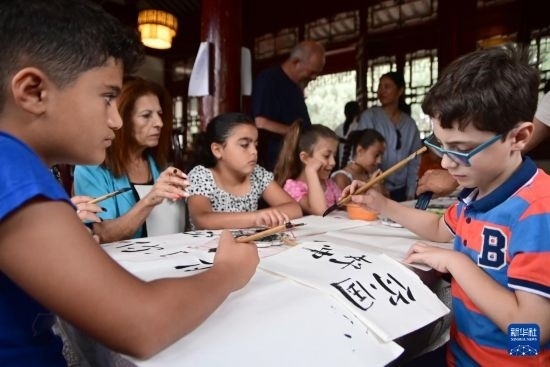 7月4日，在馬耳他桑塔露琪亞市的中國古典園林“靜園”，人們體驗(yàn)中國書法。新華社發(fā)（喬納森·博格 攝）