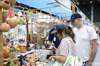 游客在蘭納博覽會特色展位上選購工藝品。人民網(wǎng)記者楊一攝