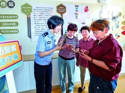 浙江湖州民警指導(dǎo)居民加入湖州“e企安”微信群，實時接收反詐信息。新華社發(fā)