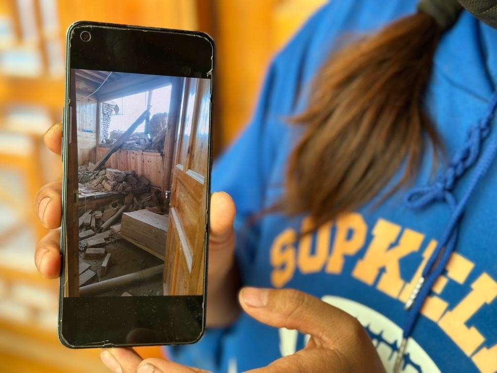 圖為7月17日拉毛東智在手機上找出地震后房屋受損的照片。新華社記者 張子琪 攝