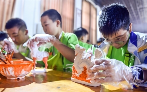 小朋友們在洛陽市孟津區(qū)朝陽鎮(zhèn)南石山村體驗(yàn)唐三彩素胎施釉技藝。圖片來源：視覺中國