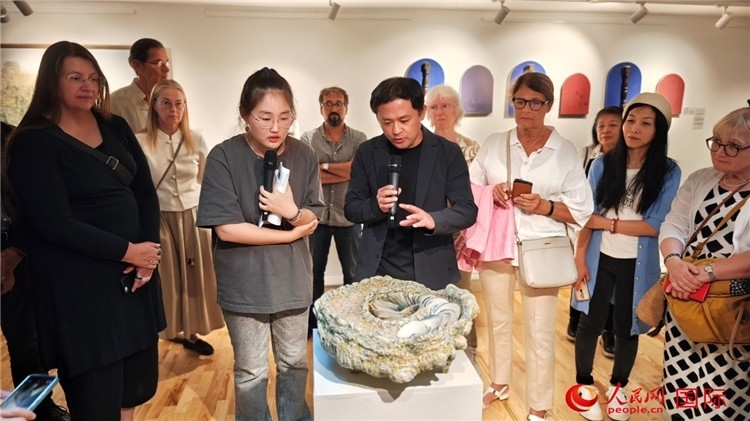 參展人、景德鎮(zhèn)陶瓷大學(xué)設(shè)計(jì)藝術(shù)學(xué)院副院長余劍峰（中）向來賓介紹參展作品。人民網(wǎng)記者 殷淼攝
